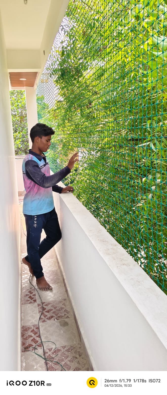 Installer fitting green balcony safety net along a corridor railing